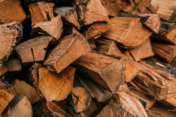 Close-up of stacked chopped firewood with visible texture, bark, and natural grain patterns in warm...