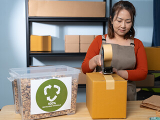 A woman using kraft paper tape to seal a cardboard box in a home-based business, highlighting eco-friendly packaging and sustainable practices in small business operations