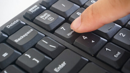 Finger pressing number 7 seven button on a black wireless computer keyboard isolated on white...