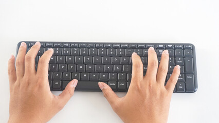 Top view of fingers typing on a black wireless computer keyboard isolated on white background