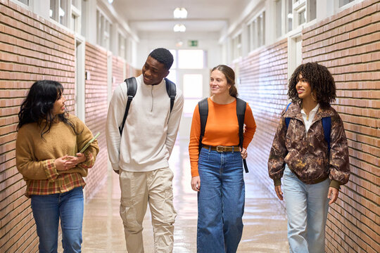 Happy students walking and talking in university corridor