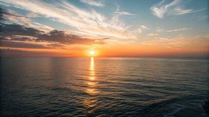 Fototapeta premium A vibrant sunset casts orange and pink hues over the ocean, with fluffy clouds scattered across the sky