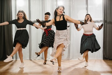 Four pinup dancers wearing polka dots are performing rock and roll moves