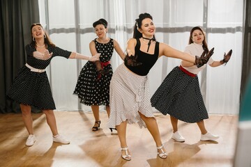 Naklejka premium Four pinup dancers wearing polka dots swinging in dance studio