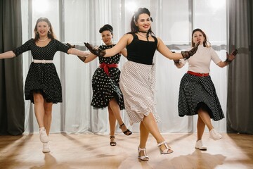 Naklejka premium Four pinup dancers wearing polka dots swinging in formation