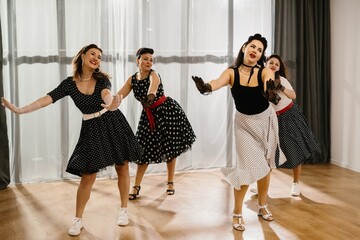Four pinup women dancing a choreography in a 1950s style