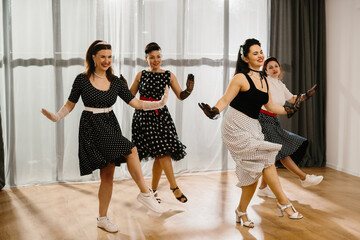 Naklejka premium Four women dancing rock and roll in 1950s style pinup clothing