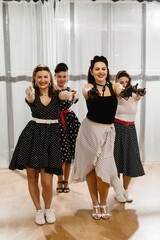 Four pinup dancers pointing fingers wearing polka dot dresses and gloves