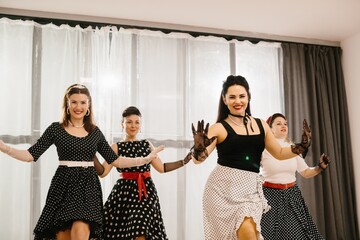 Four women wearing polka dots dancing 1950s style swing
