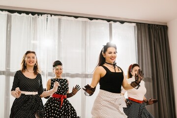 Four pinup dancers wearing polka dots are performing a choreography in dance studio