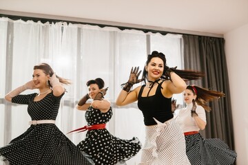Four pinup dancers wearing fifties style swinging dresses and gloves