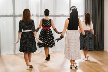 Pinup dancers wearing polka dot dresses and gloves performing rock and roll routine