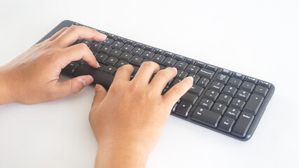 Fingers typing on a black wireless computer keyboard isolated on white background