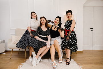 Four pinup women wearing polka dots posing on sofa