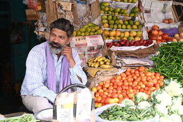 Indian shopkeeper man is selling green organic vegetables and fruits. Concept of self employment, farmer market, small business and agricultural entrepreneurship
