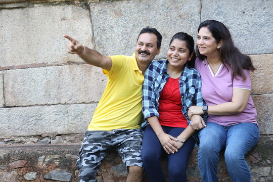 Indian happy family pointing finger to other side while spending and fun at park - Powered by Adobe