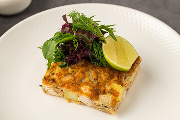 Spanish tortilla with potato and chicken, topped with fresh greens and lime