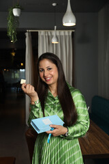 Beautiful young Indian woman holding gift box with sweet chocolate candies in a cafe.