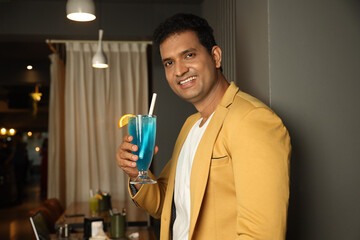 Indian young man drinking fresh drink cocktail at restaurant 