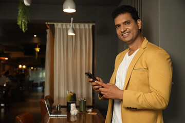 Indian handsome man using mobile phone at cafe. wearing formal suit. Concept : Mobile Banking...