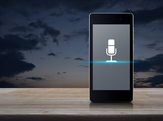 Microphone flat icon on modern smart mobile phone screen on wooden table over sunset sky, Business communication online concept