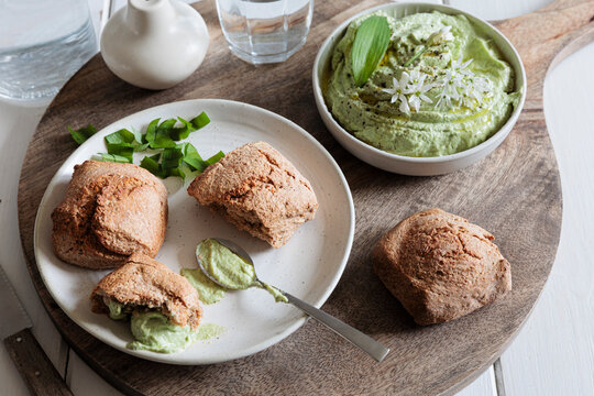 Homemade bread rolls with wild garlic dip and herb cream cheese on a wooden board