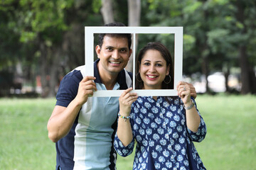 Indian happy young couple holding Papercut Family House.. standing posing and looking in front of...