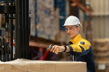 Man professional worker wearing safety uniform and white hard hat using barcode reader scanning box...