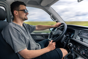 Smiling man driving car. Confident driver in motion. Comfortable road trip.