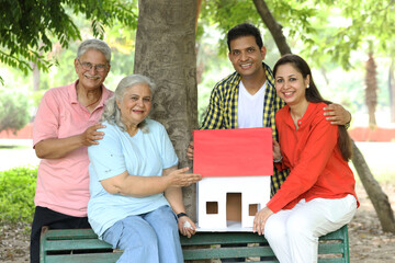 Indian happy family holding home shape model.
Concept - Real Estate theme