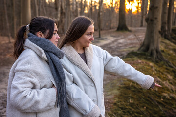 Two women in the forest. Woman pointing at the scenery. People in nature.