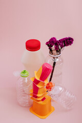 Conceptual balancing still life with plastic and flower on pink, theme of recycling, waste...