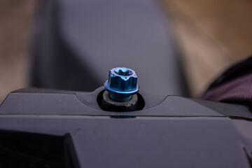 A macro close-up of a blue titanium bolt or nut on a motorcycle or car part. A concept of vehicle...