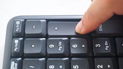 Finger pressing punctuation key button on a black modern wireless computer keyboard isolated on...