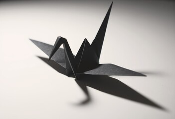 Minimalist black origami crane with striking shadows on a white background