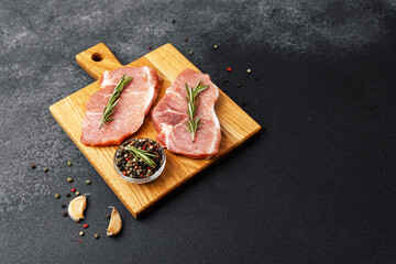 Fresh pork chops with rosemary and spices on a wooden cutting board