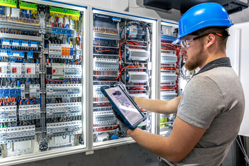Switchboard check. Electrician with tablet. Technology in action.
