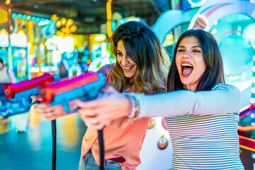Two happy friends playing with toy guns in an arcade center
