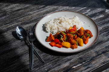 Pork in sweet and sour sauce with boiled rice on a plate. 
