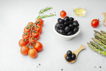 Bowl of black olives with tomatoes asparagus and cooking ingredients