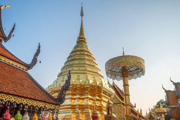 Fototapeta premium Golden stupa at Buddhist temple Wat Phra That Doi Suthep with ornate golden ceremonial umbrella at sunset in Chiang Mai, Thailand. Thai religious architecture. Travel and touristic landmark