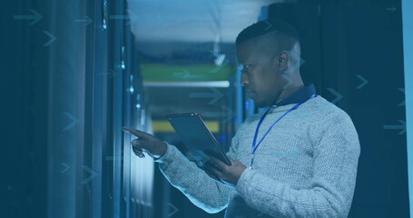 IT technician pointing tablet at blinking server module in data center aisle, with racks and badge