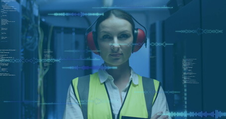 Monitoring tech in high-vis vest red earmuffs scanning racks in blue LED data center, code overlays