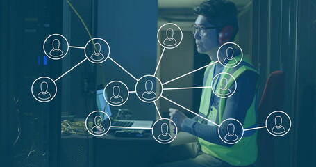 Korean technician in vest and headphones configuring network on laptop in server room, copy space