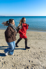 Two women walking on the seashore. Two friends spending time together. Sea.