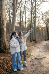 Two women in the forest. Woman pointing at the scenery. People in nature.