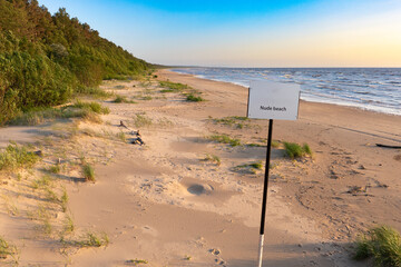 nude beach sign with blue water