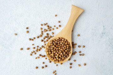 wooden spoon with coriander seeds on white background