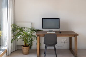desktop computer with big empty screen, modern workplace interior with copyspace, white wall