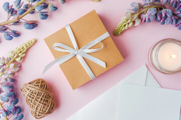 Gift box with ribbon, flowers and candle on pink background